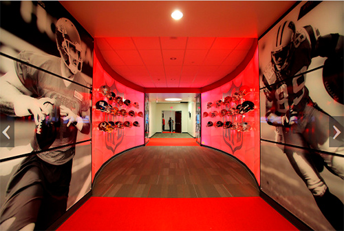 red glowing hallway with football helmets and university of Utah branding