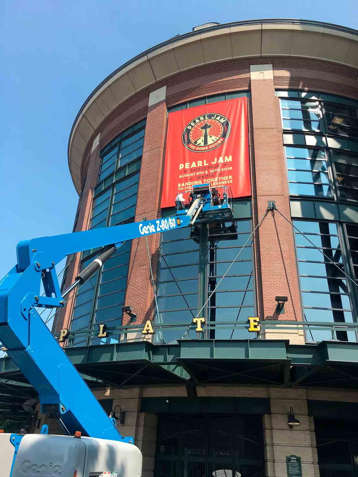 blue crane putting up large format printed banner for Pearl Jam concert